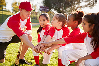 Youth sports coach talking with team of young baseball players