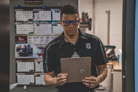 Coach reading clipboard in front of office.
